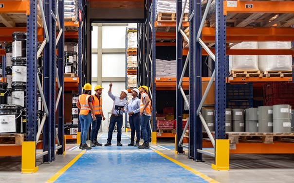Forperson talking to a group of employees in a warehouse